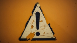 a triangle shaped sign on a yellow wall