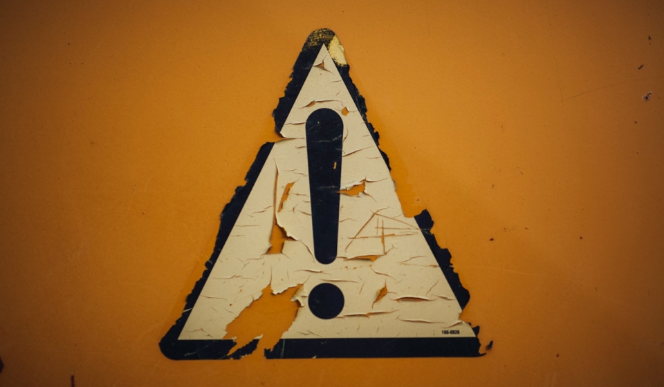 a triangle shaped sign on a yellow wall